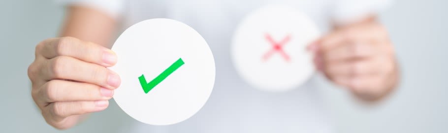 An image of a student holding a sign with a green tick and a red cross on it