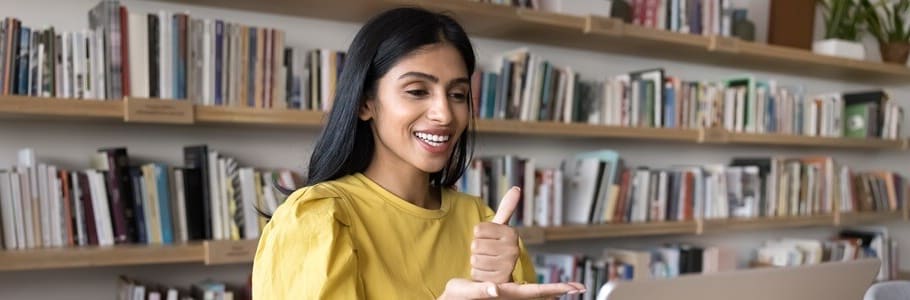 A student communicating with British Sign Language through a laptop screen.