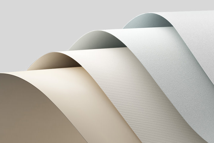 Wavy layers of stationery in various neutral shades such as white, beige and light grey, with changing surface textures, draped on top of each other.