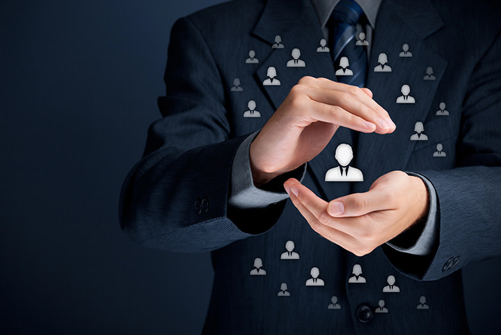 A businessman in a suit protects with his hands a symbol of a person, surrounded by other small person symbols, symbolizing customer protection and CRM.