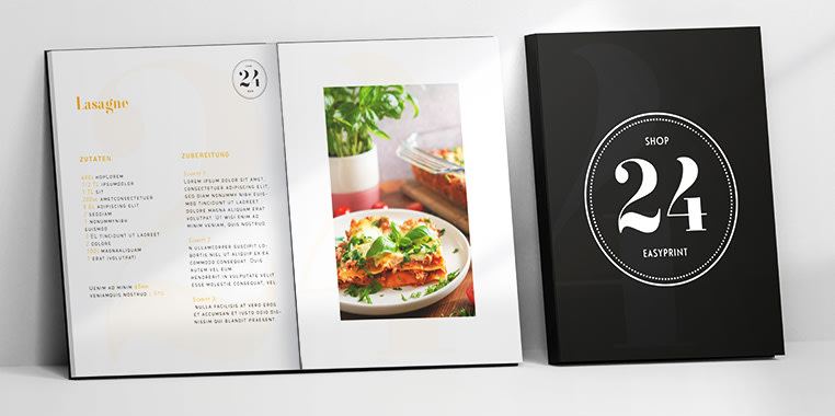 Rezeptbücher mit schwarzem Einband und weißer Schrift, geöffnete Doppelseite mit Lasagne-Rezept und Foto auf hellem Hintergrund.