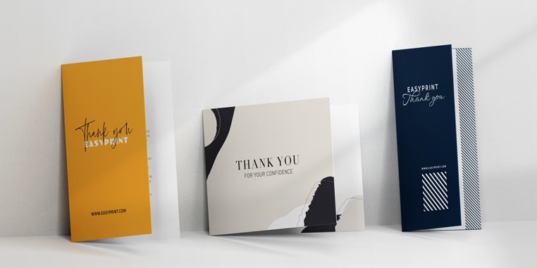 Tre opretstående takkekort i forskellige designs – gule til venstre med sorte bogstaver, beige i midten med et moderne layout og mørkeblå til højre med hvid typografi og en URL – ideelle til personlige takkesedler og kortudskrivning i høj kvalitet.