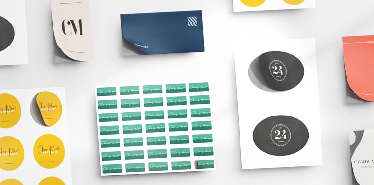 Ulike etiketter og klistremerker i gult, grønt, blått og svart på hvit bakgrunn, inkludert runde, rektangulære og ovale former i ulike design.