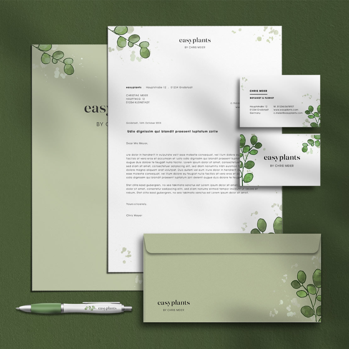 Skrivesaker med botanisk design – bestående av brevpapir, konvolutt, visittkort og kulepenn på grønn bakgrunn, ideelt for blomsterbruk samt hagearbeid og landskapsarbeid