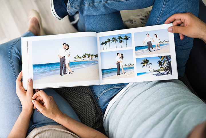 Par ser sammen på feriefotobok – fotografert over skulderen, koselig øyeblikk med delte minner