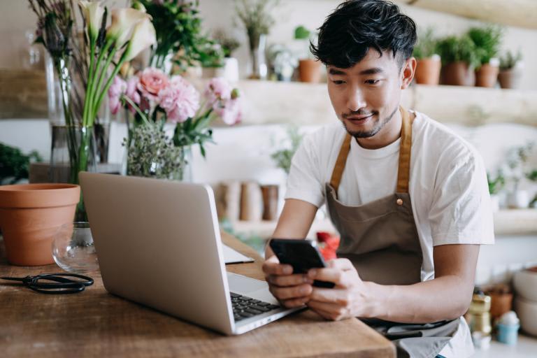 Young man on his mobile phone with laptop