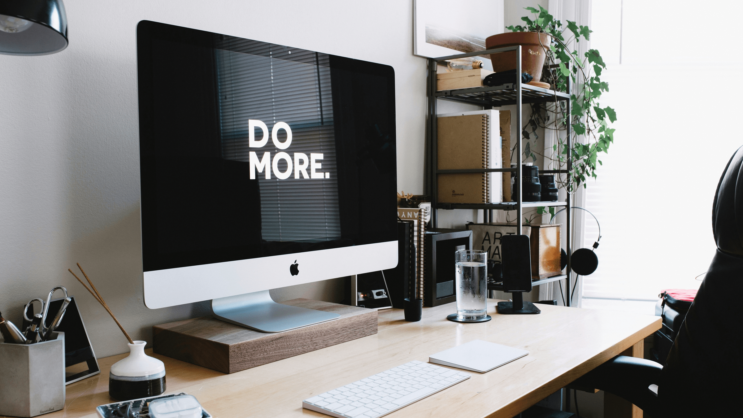 Bureau moderne avec iMac affichant "DO MORE.", évoquant la productivité et les étapes de création web.