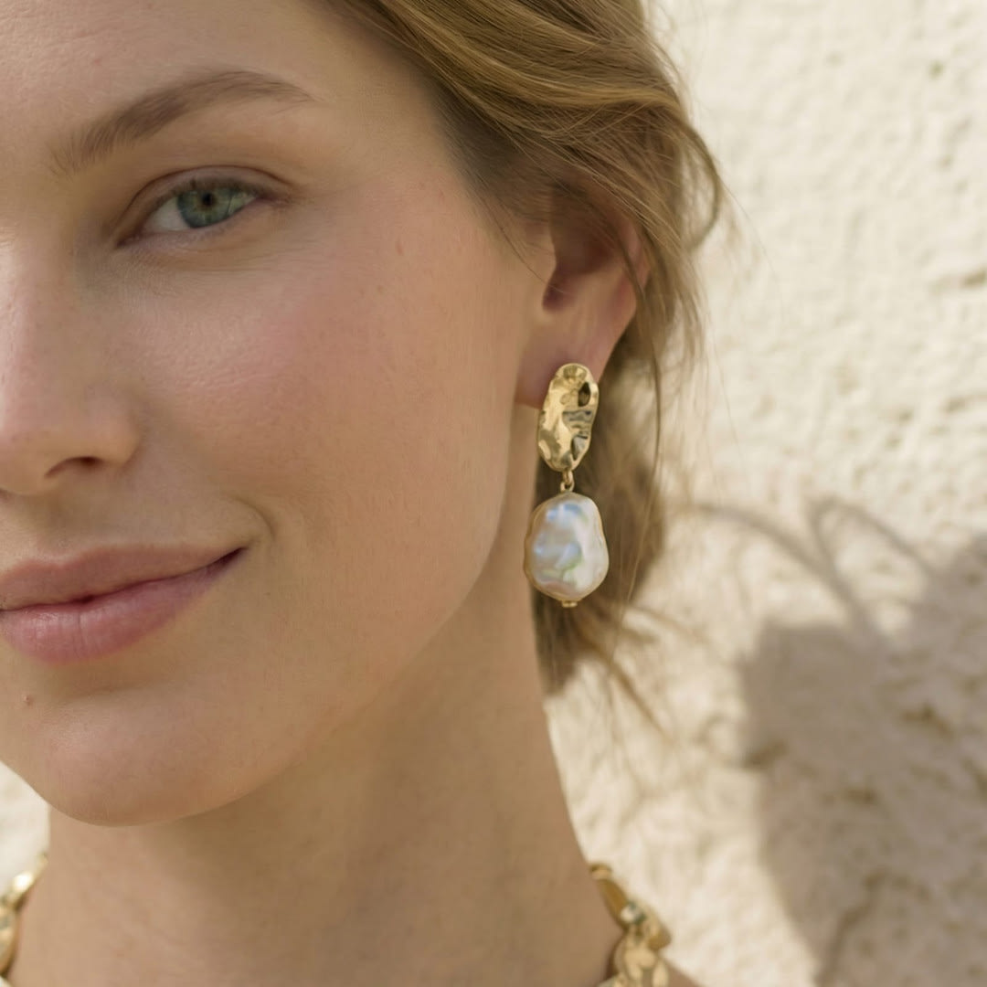 Close-up of Unur keshi pearl statement earrings with gold leaf accents worn on model