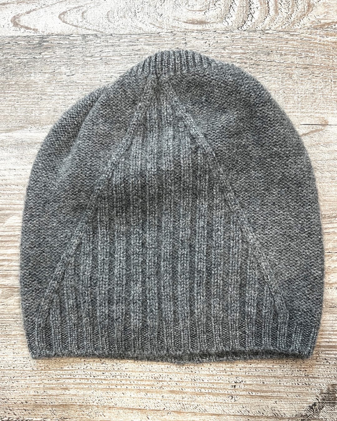 Grey cashmere beanie on neutral background, flat view