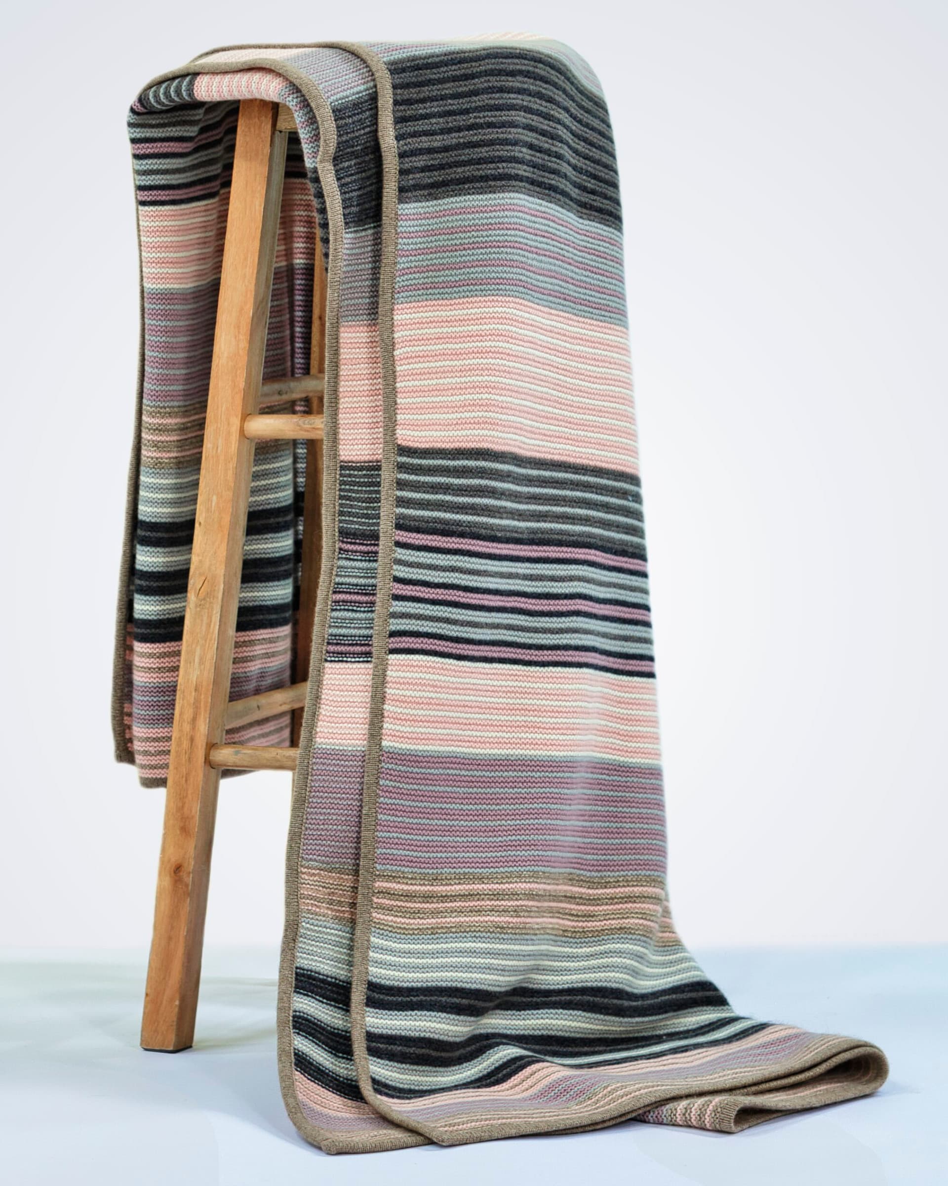 heavyweight knitted pink striped cashmere blanket draped over a chair