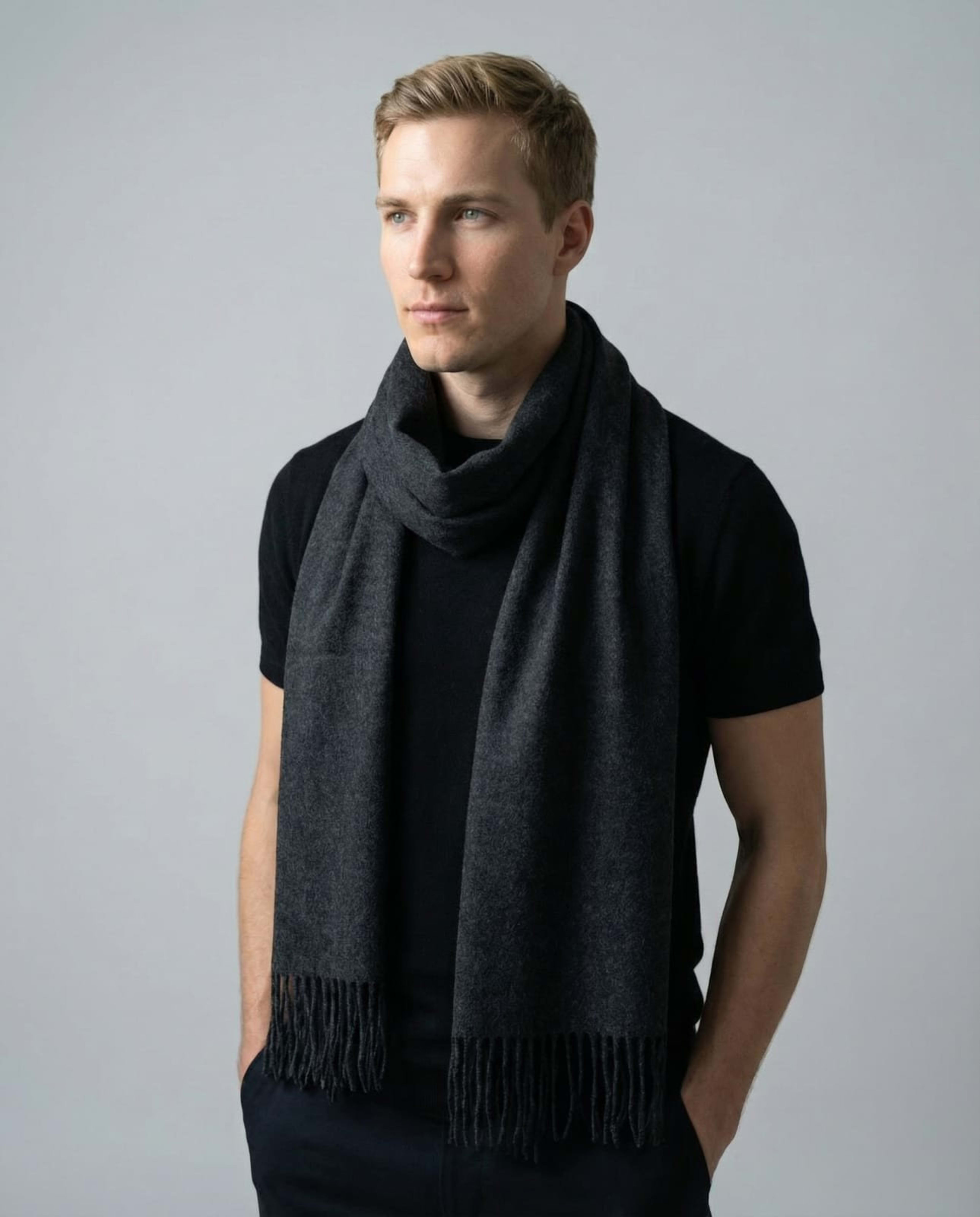 Man wearing a unisex woven cashmere scarf in dark grey with tassel fringe