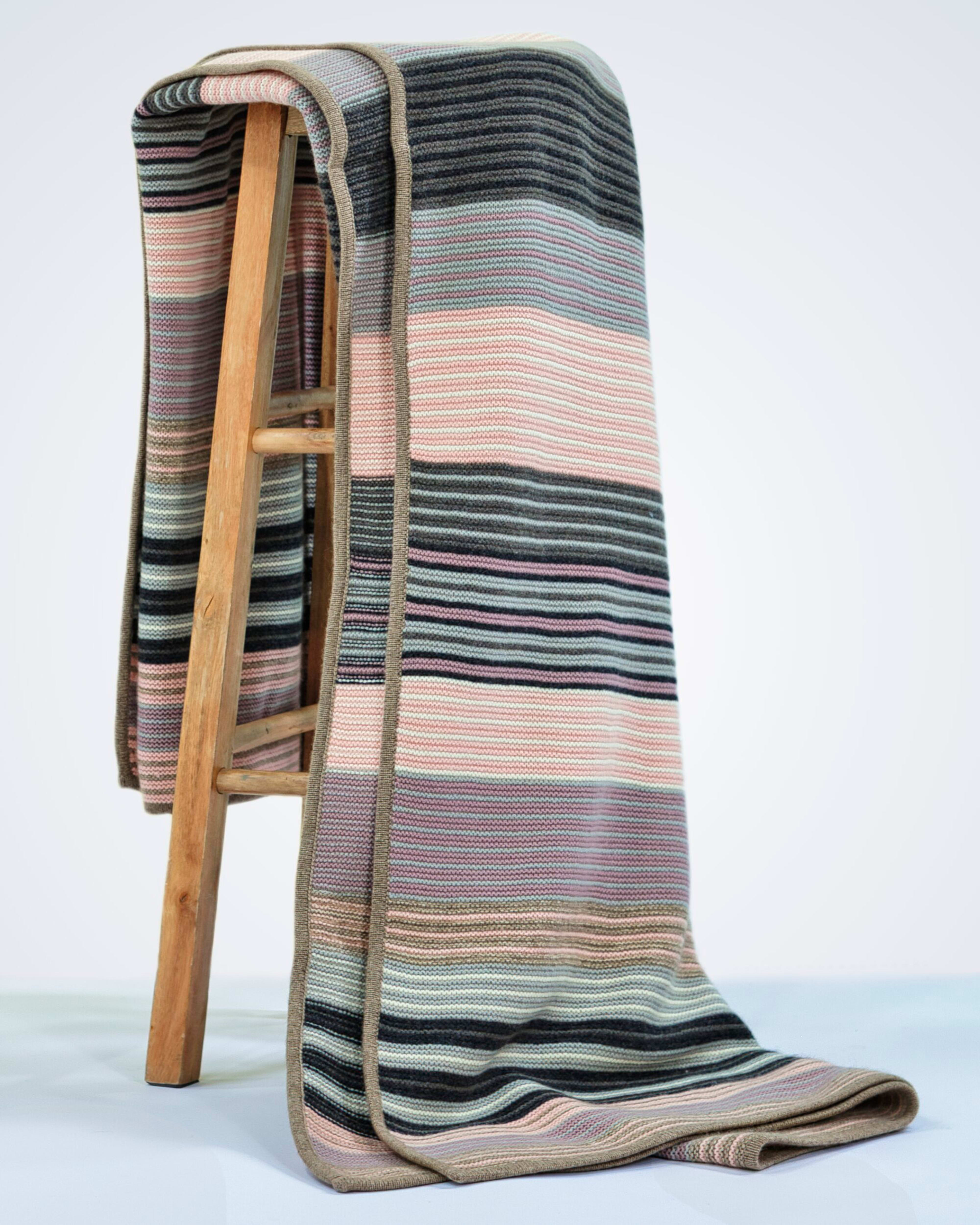 heavyweight knitted pink striped cashmere blanket draped over a chair