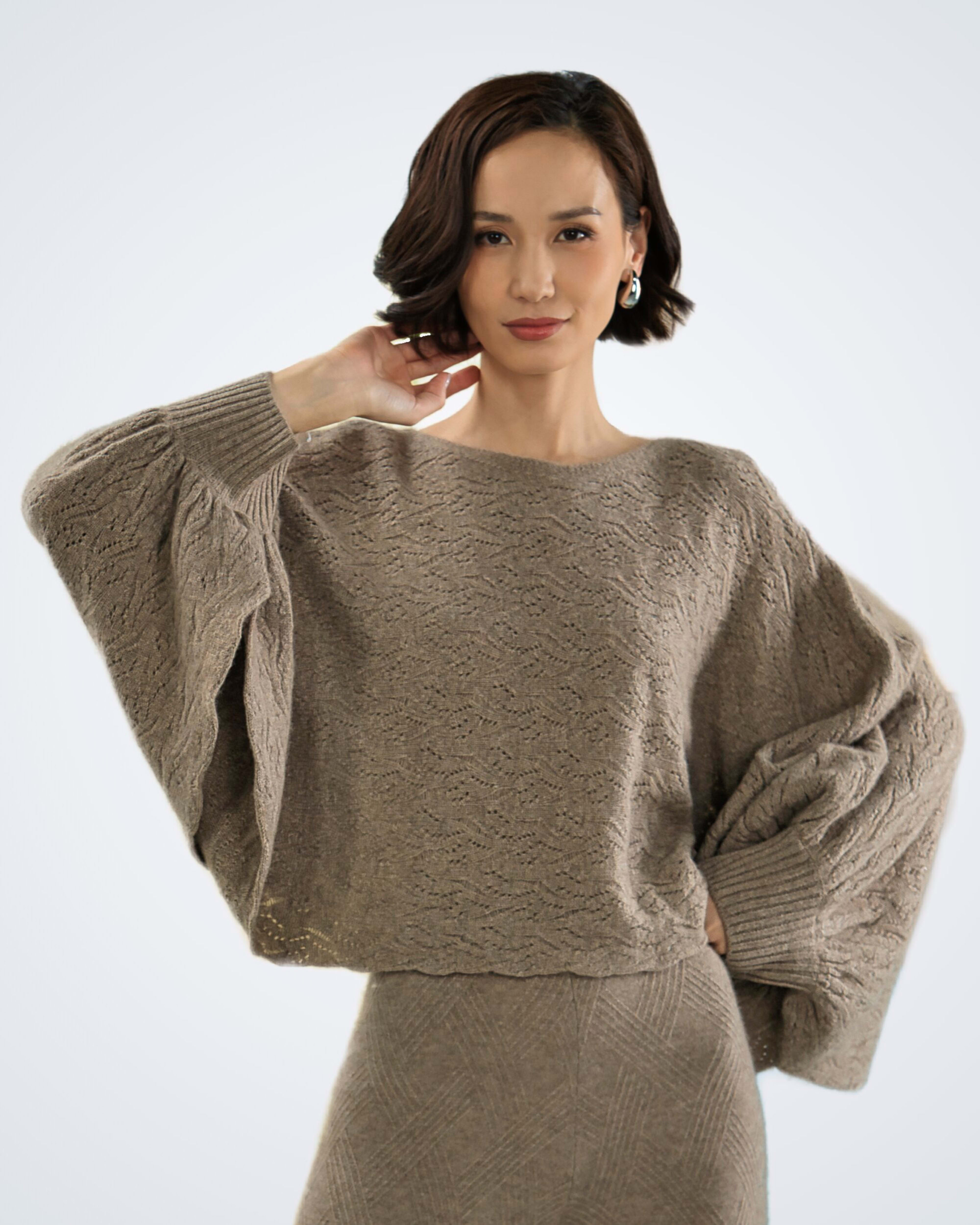Woman wearing a patterned poncho-style cashmere jumper