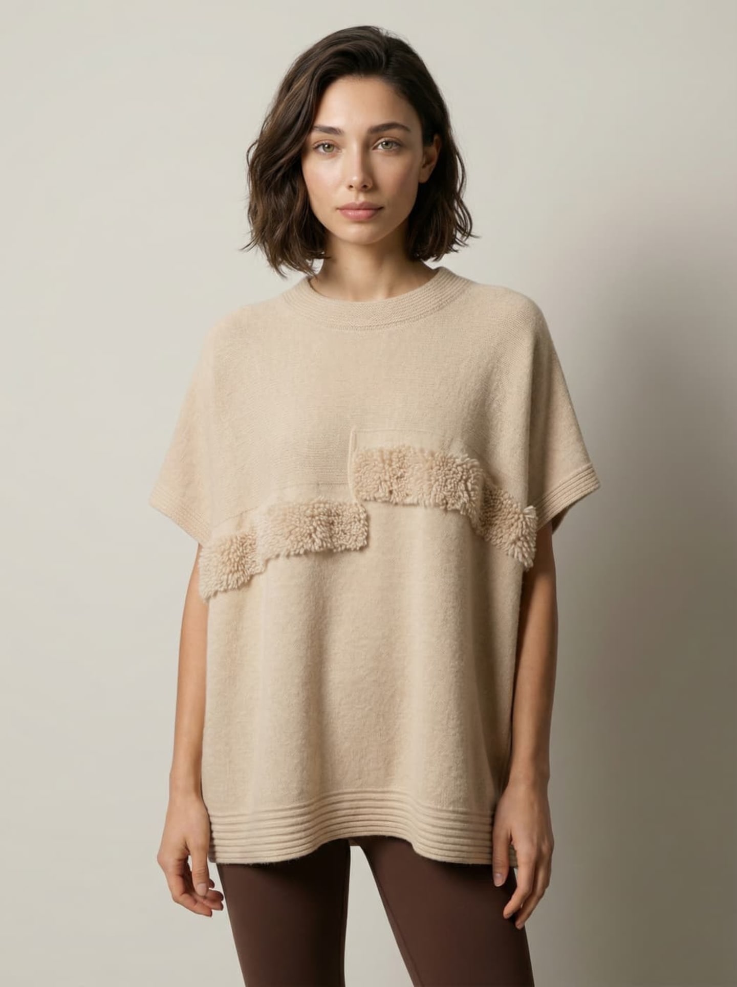 Front view of model wearing Unur's natural beige cashmere cape top with boucle panels