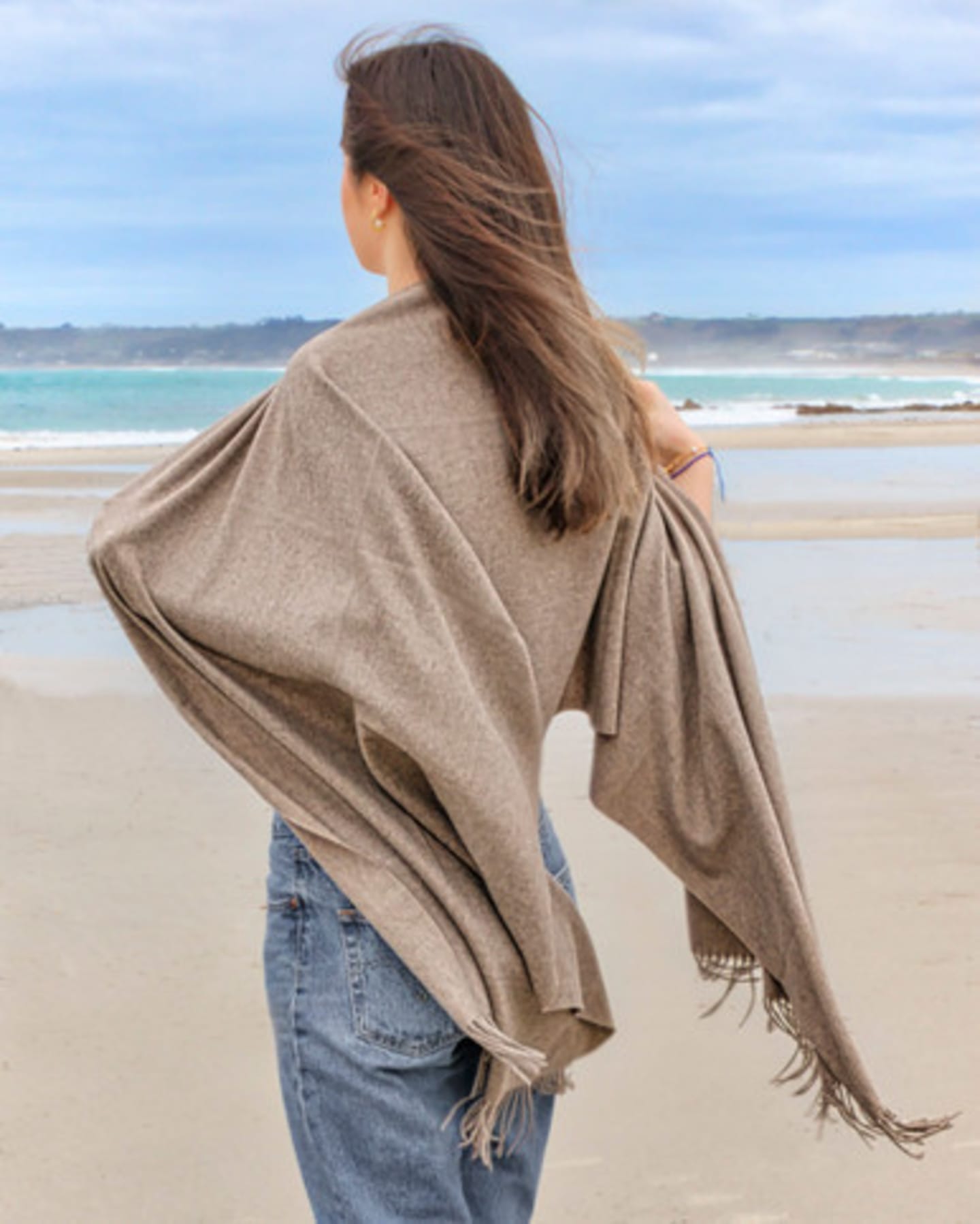 woman outdoors wearing a large natural brown cashmere shawl, rear view