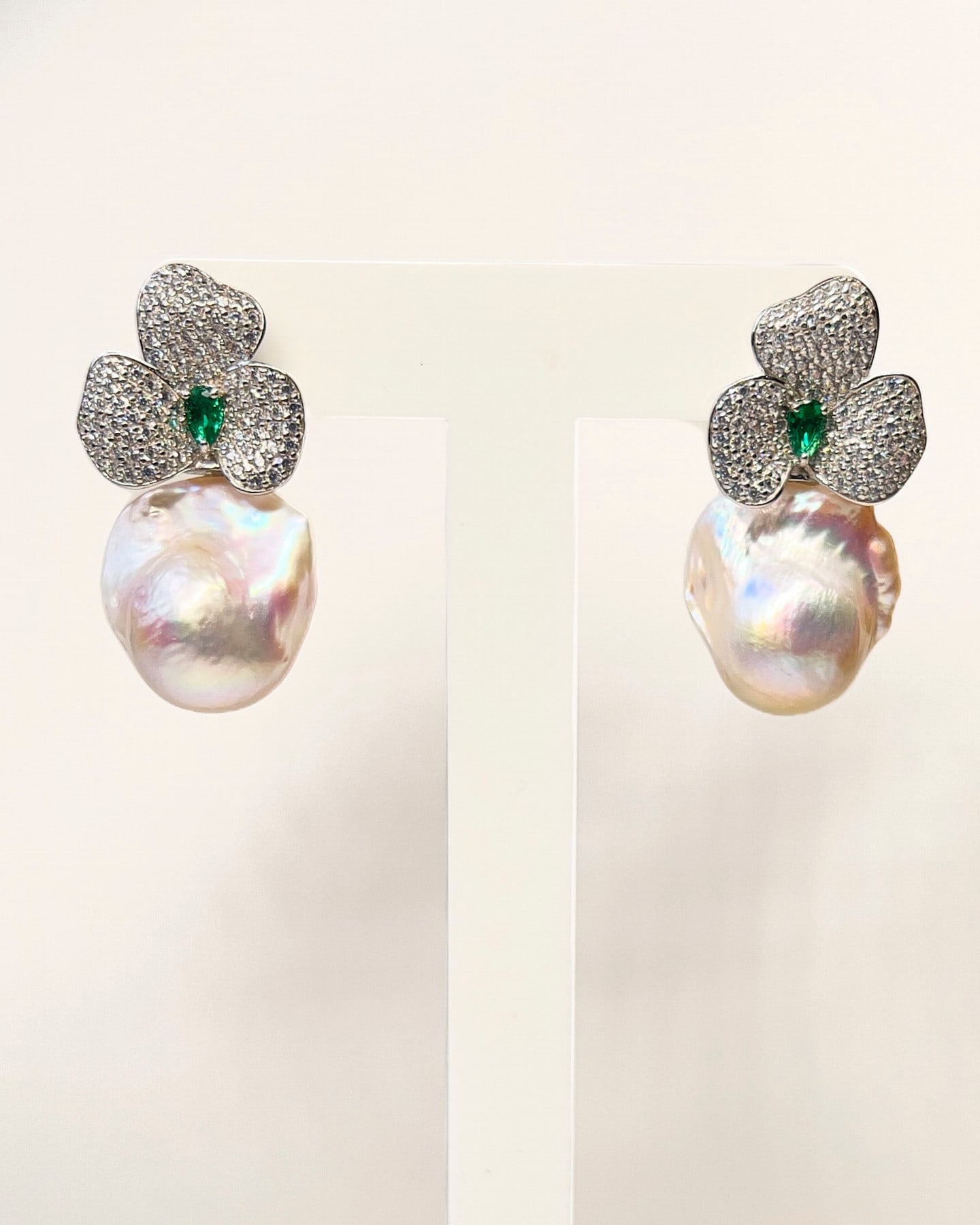 Pair of Signature Baroque Pearl & Green Crystal Flower Drop Earrings on a white display bust, mirror-matched.