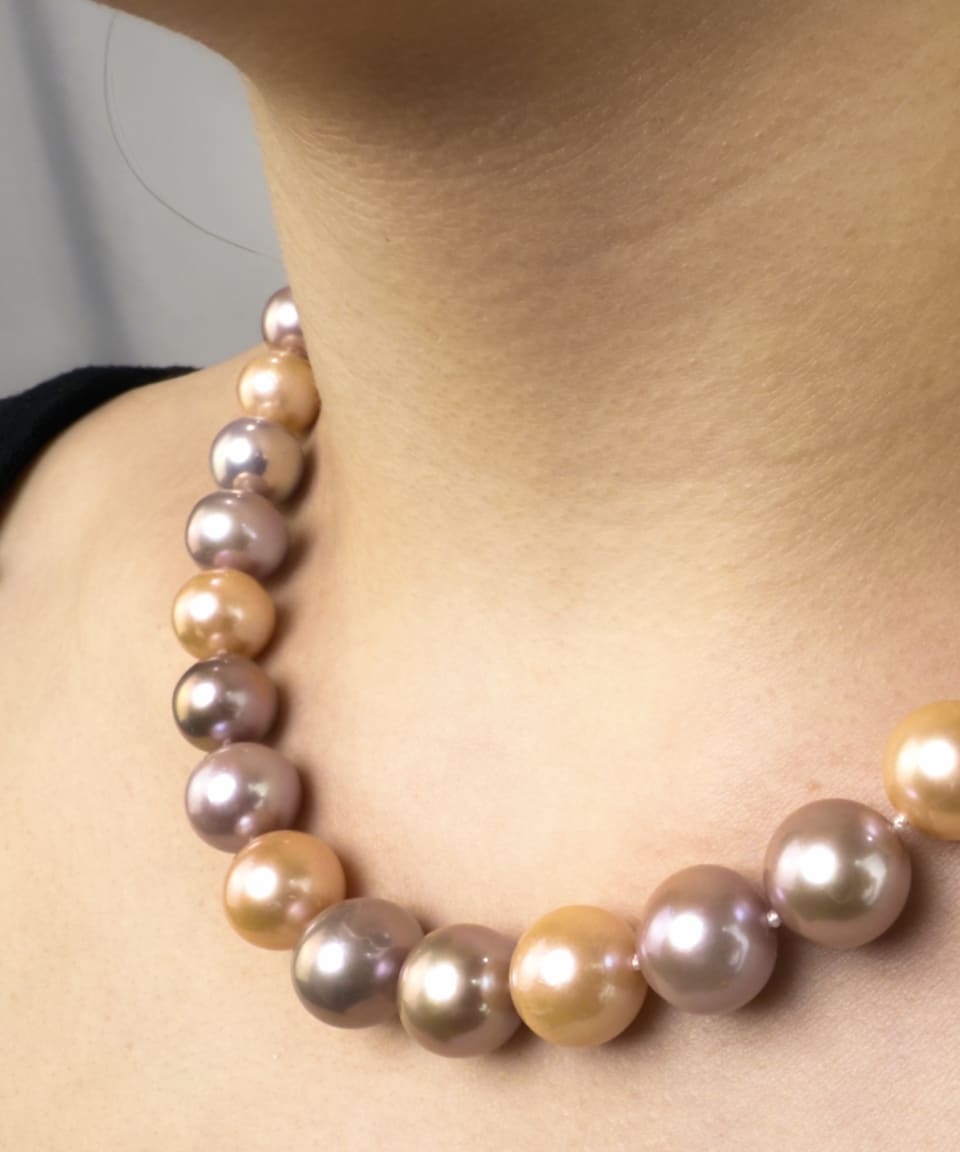 Model wearing classic necklace with peach and purple round pearls