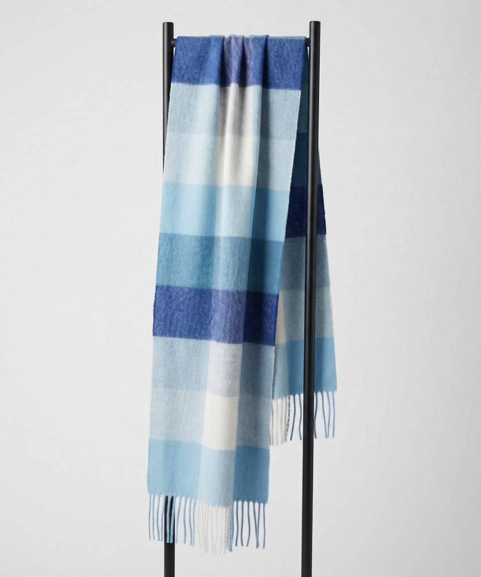 Unisex woven cashmere scarf in check blue, draped over a hanger