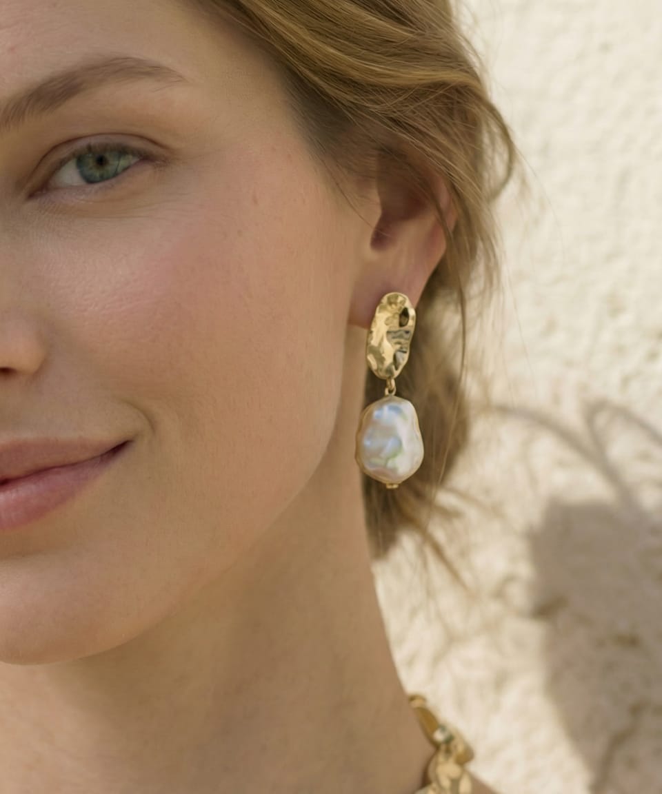 Close-up of Unur keshi pearl statement earrings with gold leaf accents worn on model