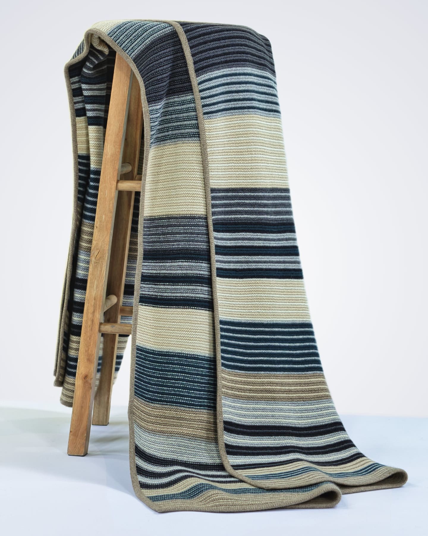 heavyweight knitted navy blue striped cashmere blanket draped over a chair