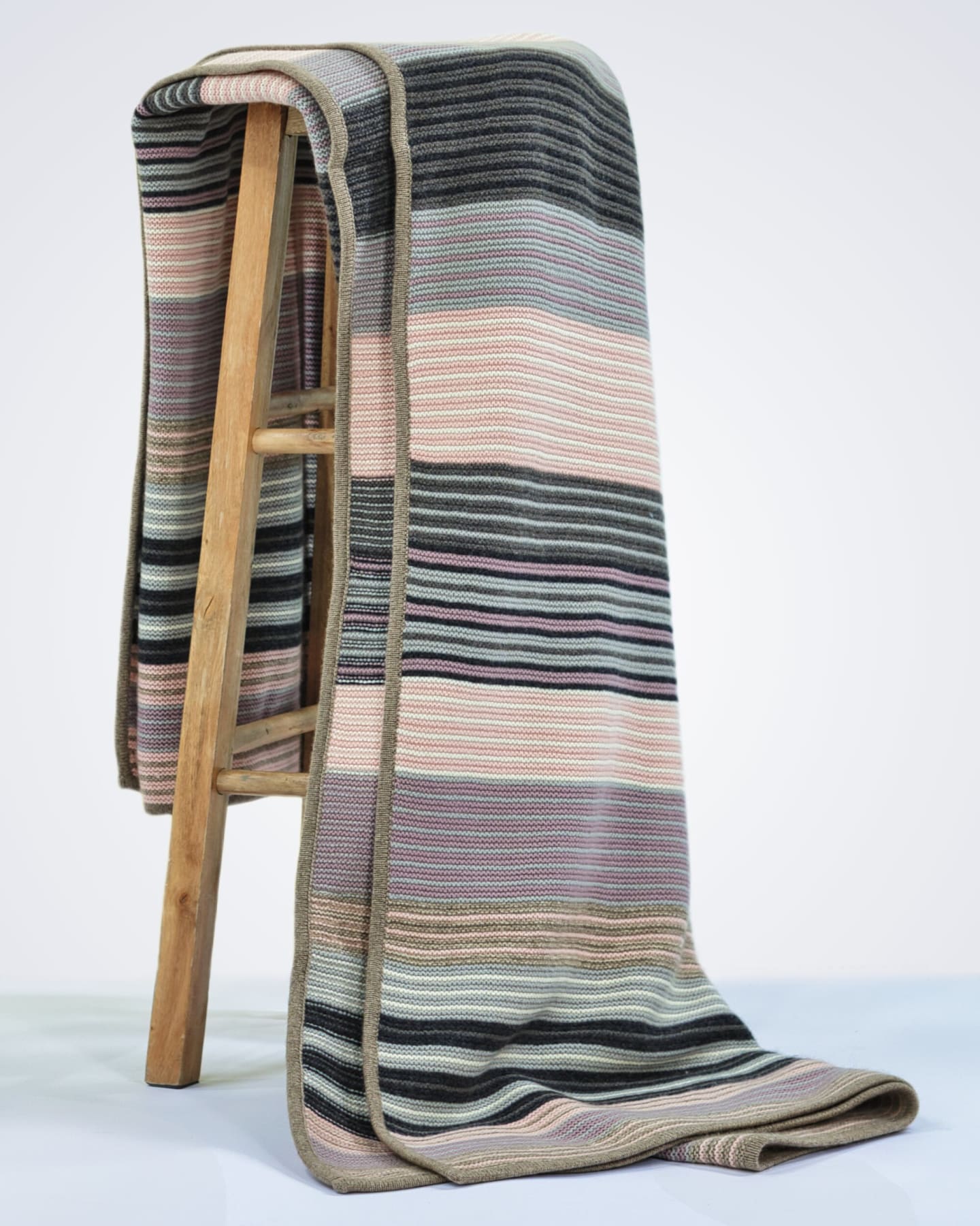 heavyweight knitted pink striped cashmere blanket draped over a chair