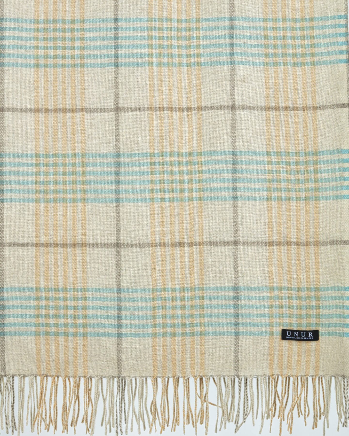 Close-up detail of cashmere plaid weave and tasselled fringe on Unur wrap shawl