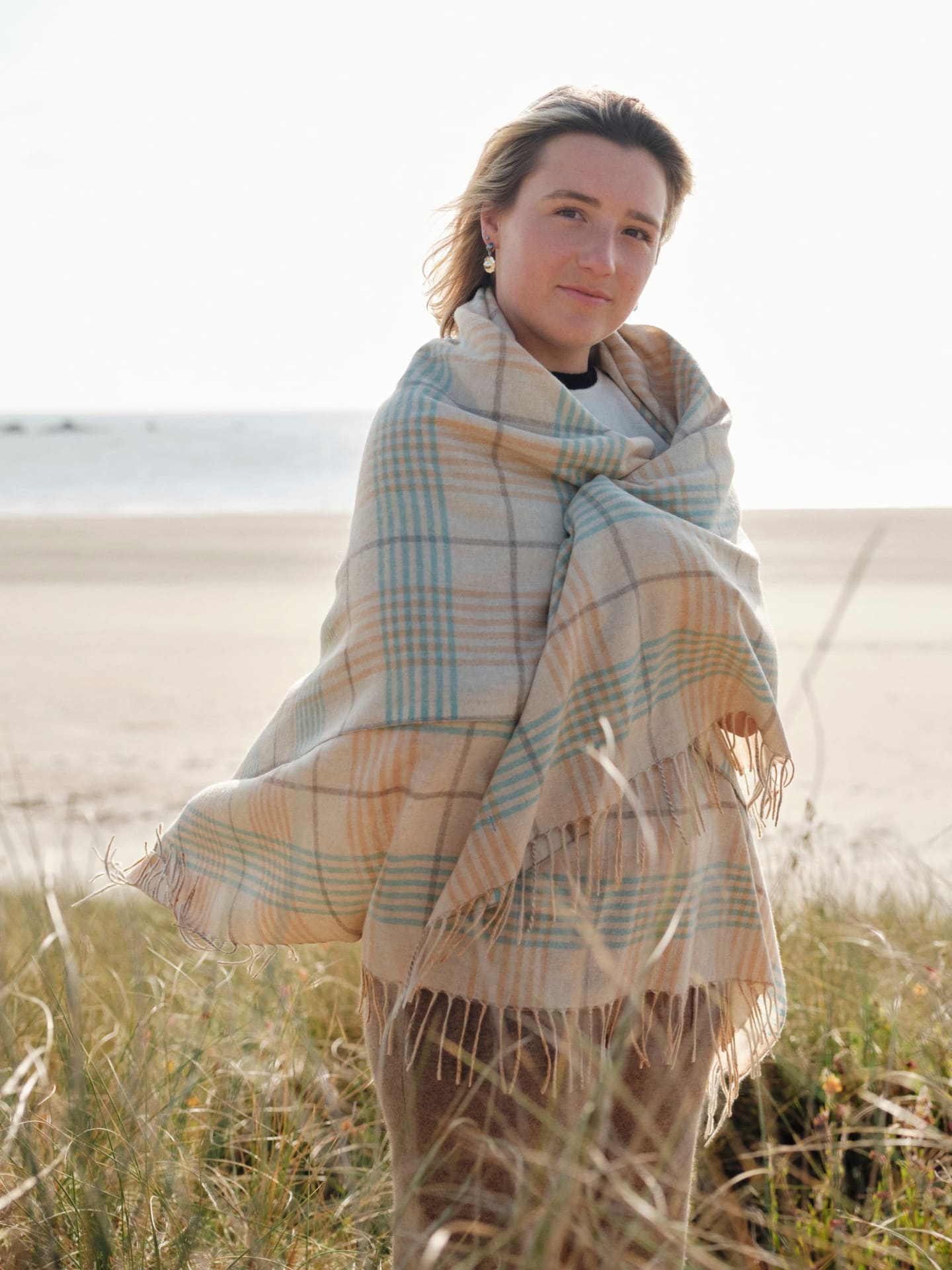 Woman wearing an Unur cashmere plaid wrap shawl outdoors, paired with casual attire