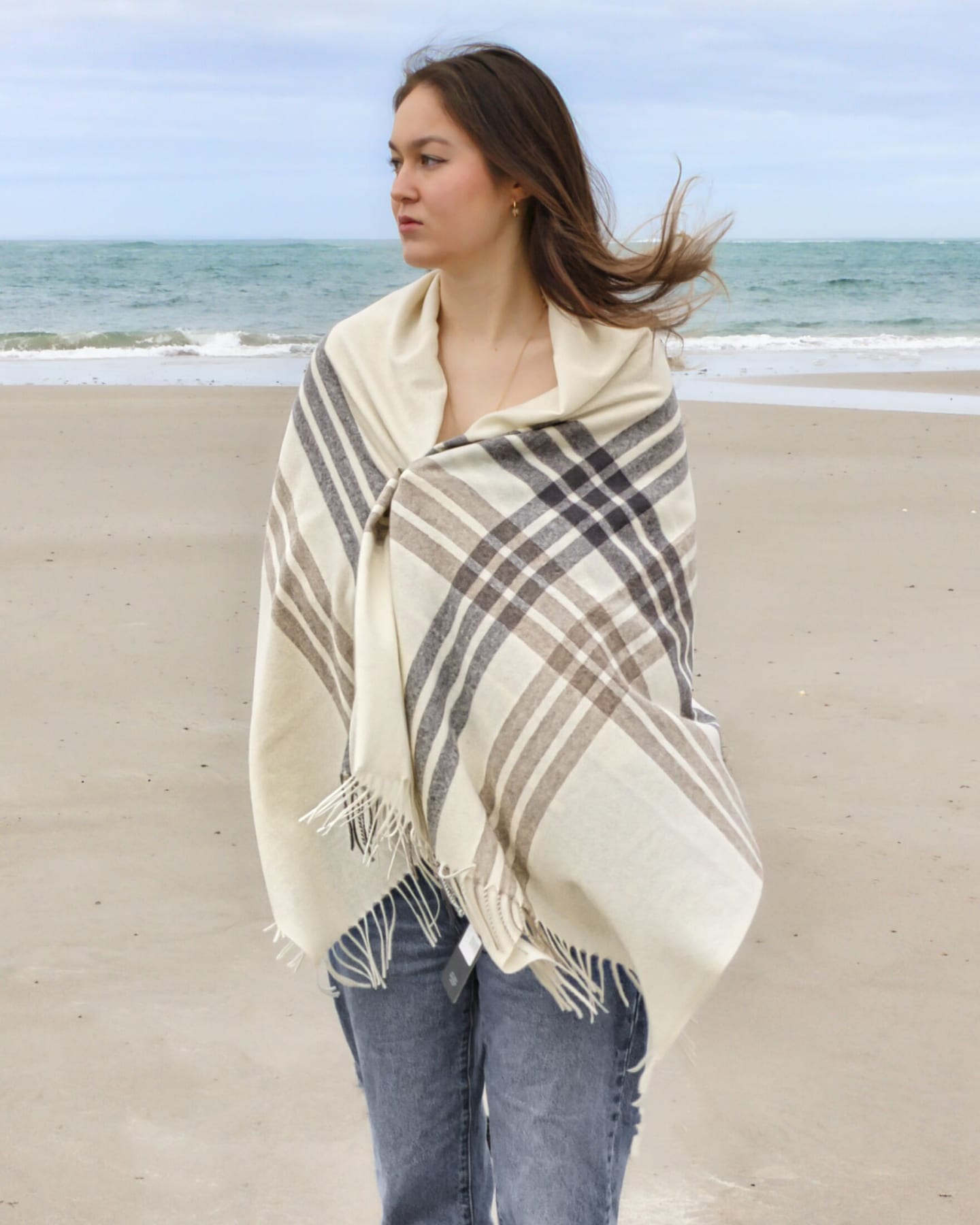 Woman on beach wrapped in a natural white plaid cashmere wrap shawl