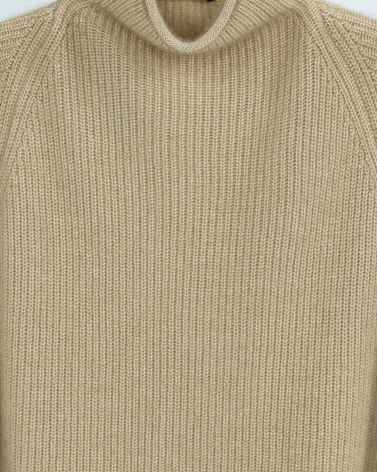 Close-up detail of ribbed cashmere knit texture in natural beige