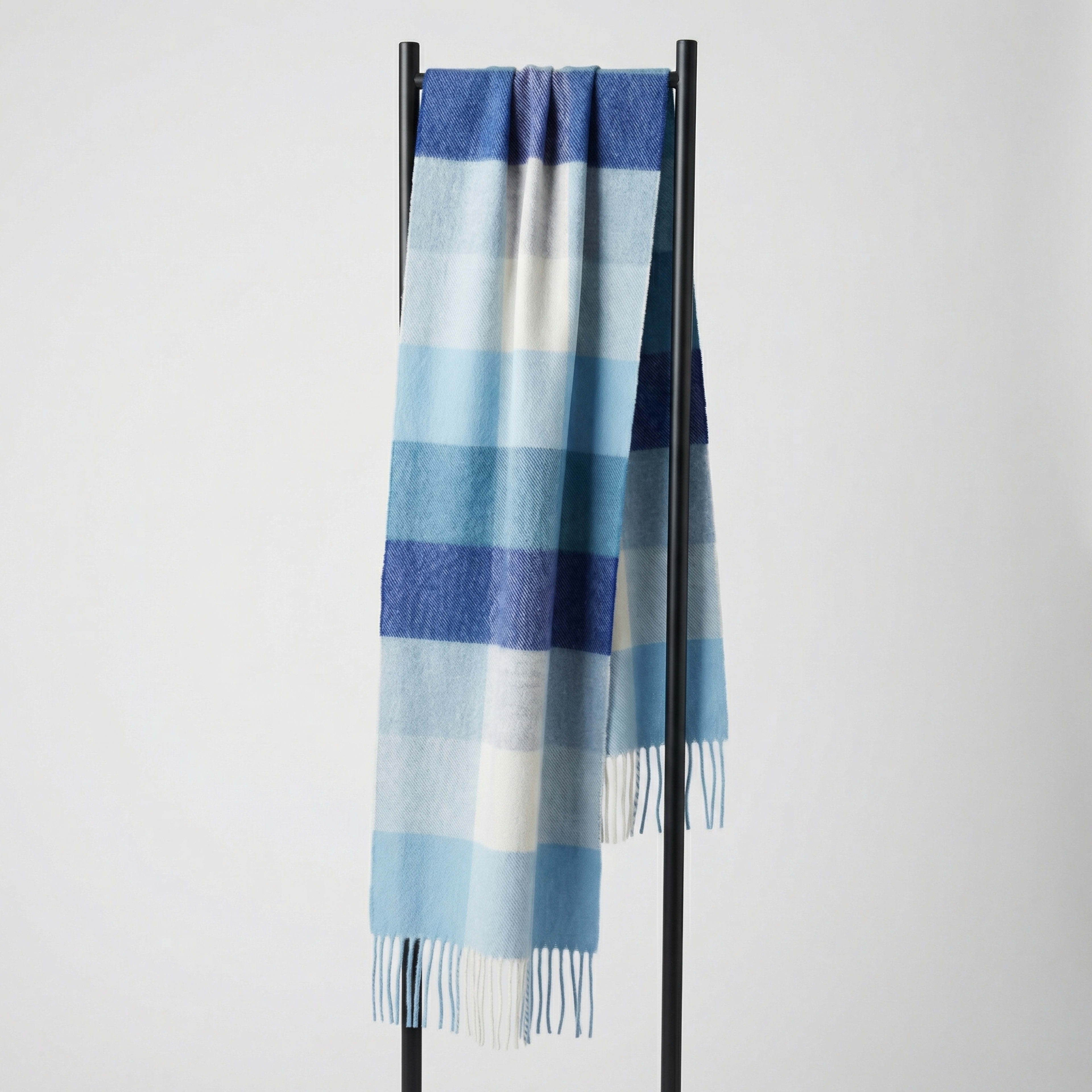 Unisex woven cashmere scarf in check blue, draped over a hanger