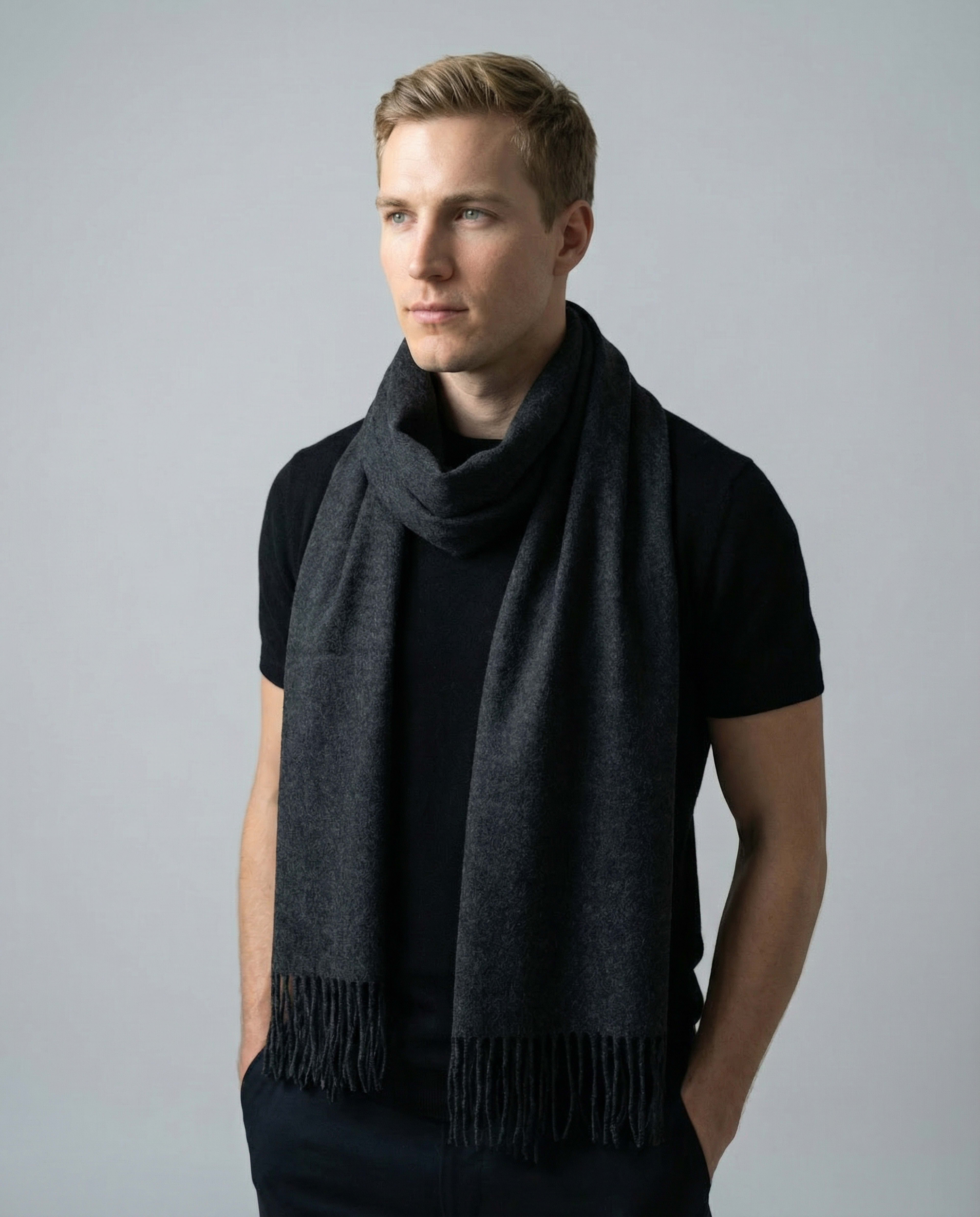 Man wearing a unisex woven cashmere scarf in dark grey with tassel fringe