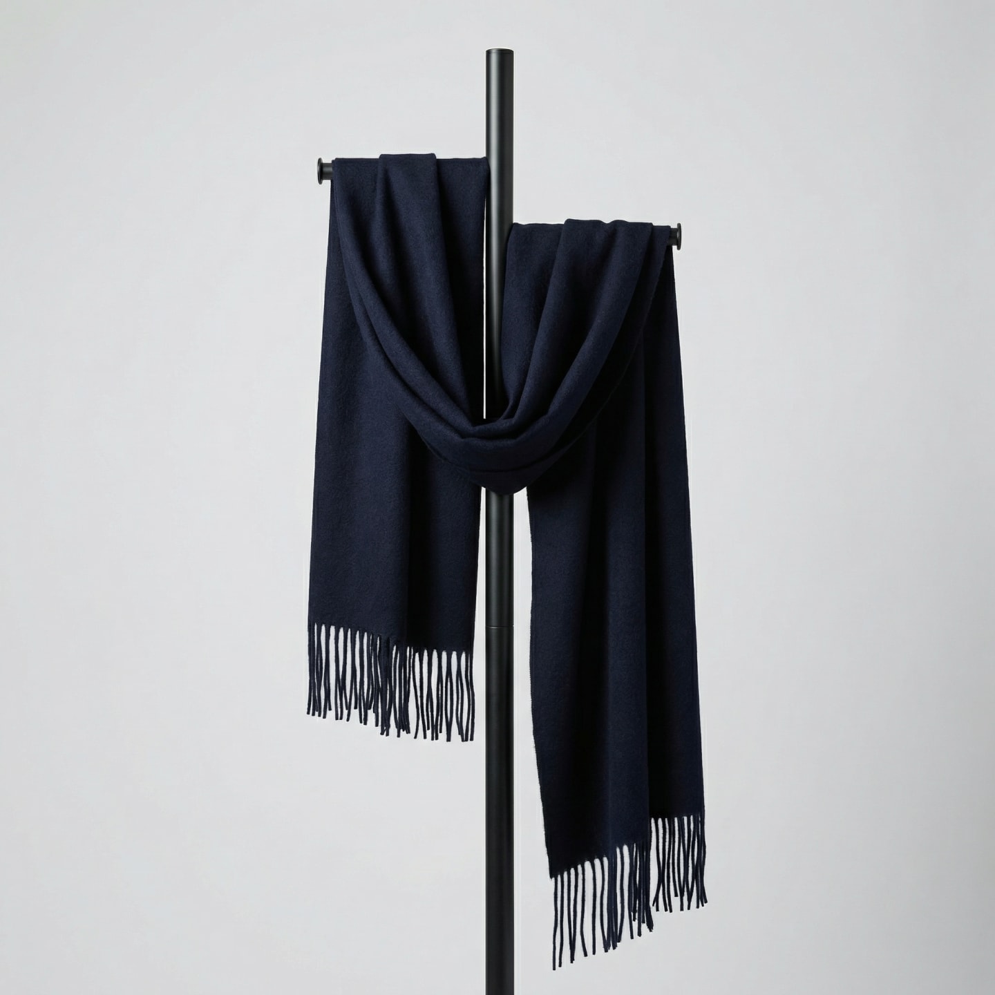 Unisex woven cashmere scarf in navy blue with tassel fringe, draped over a display rod against a white background