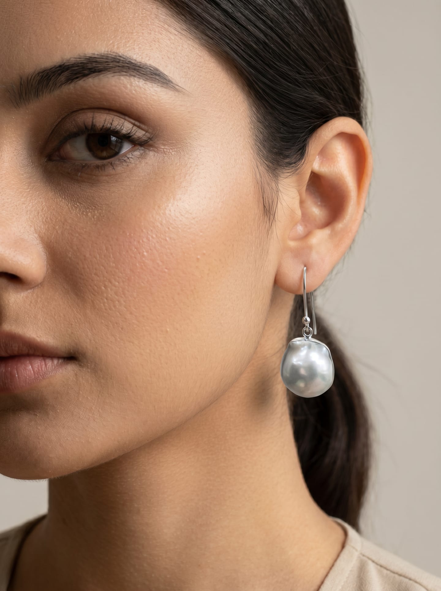 Model wearing the Signature Baroque Pearl Hook Earring, a baroque freshwater pearl on a polished silver hook.