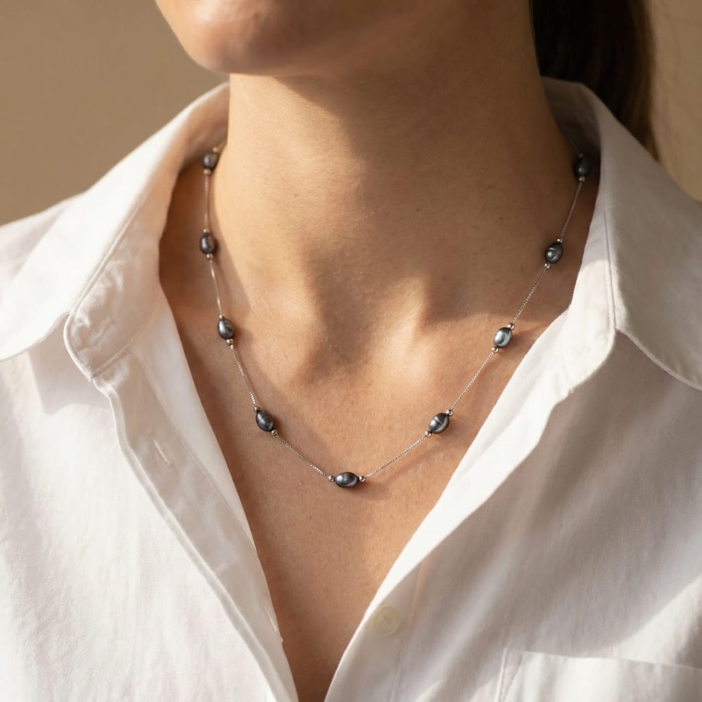 Close-up of the Classic Oval Pearl Satellite Chain Necklace in black, dark freshwater pearls flanked by small silver beads on a fine cable chain.