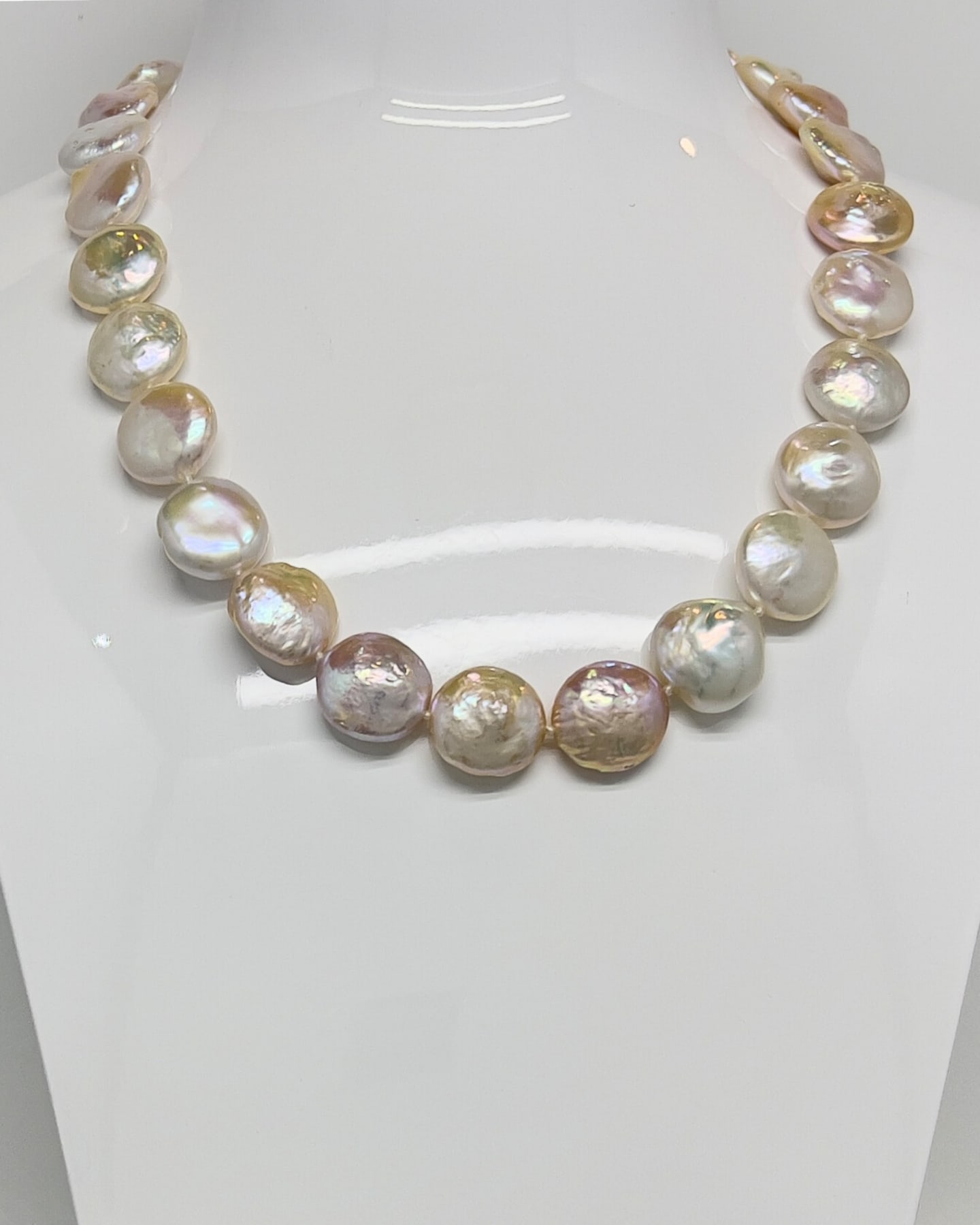 Close-up of a multi-colour button pearl strand necklace, large flat pearls in peach, champagne, ivory and lavender tones with strong rainbow iridescence