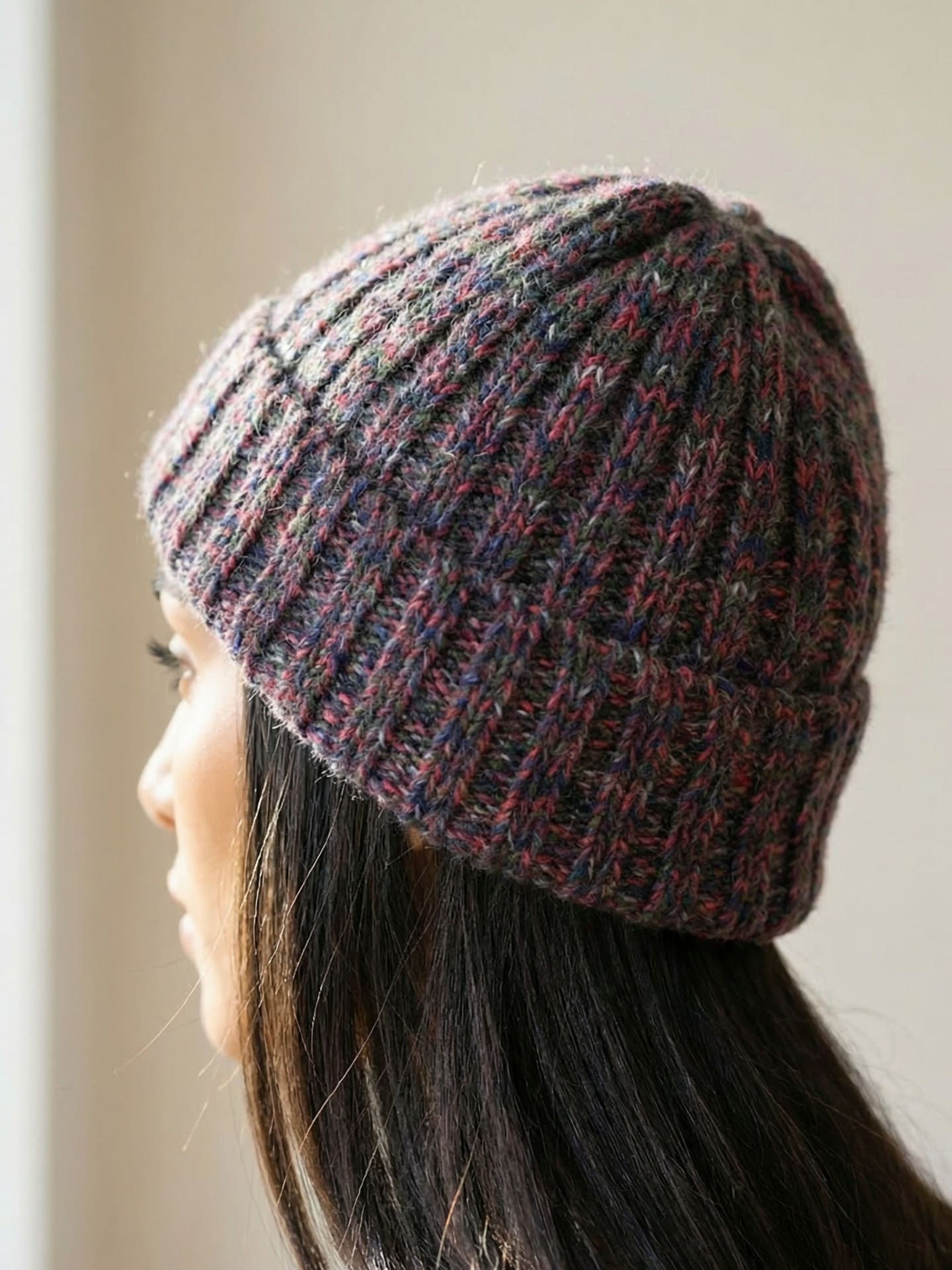 Rear view of woman wearing chunky ribbed yak wool hat in mottled red