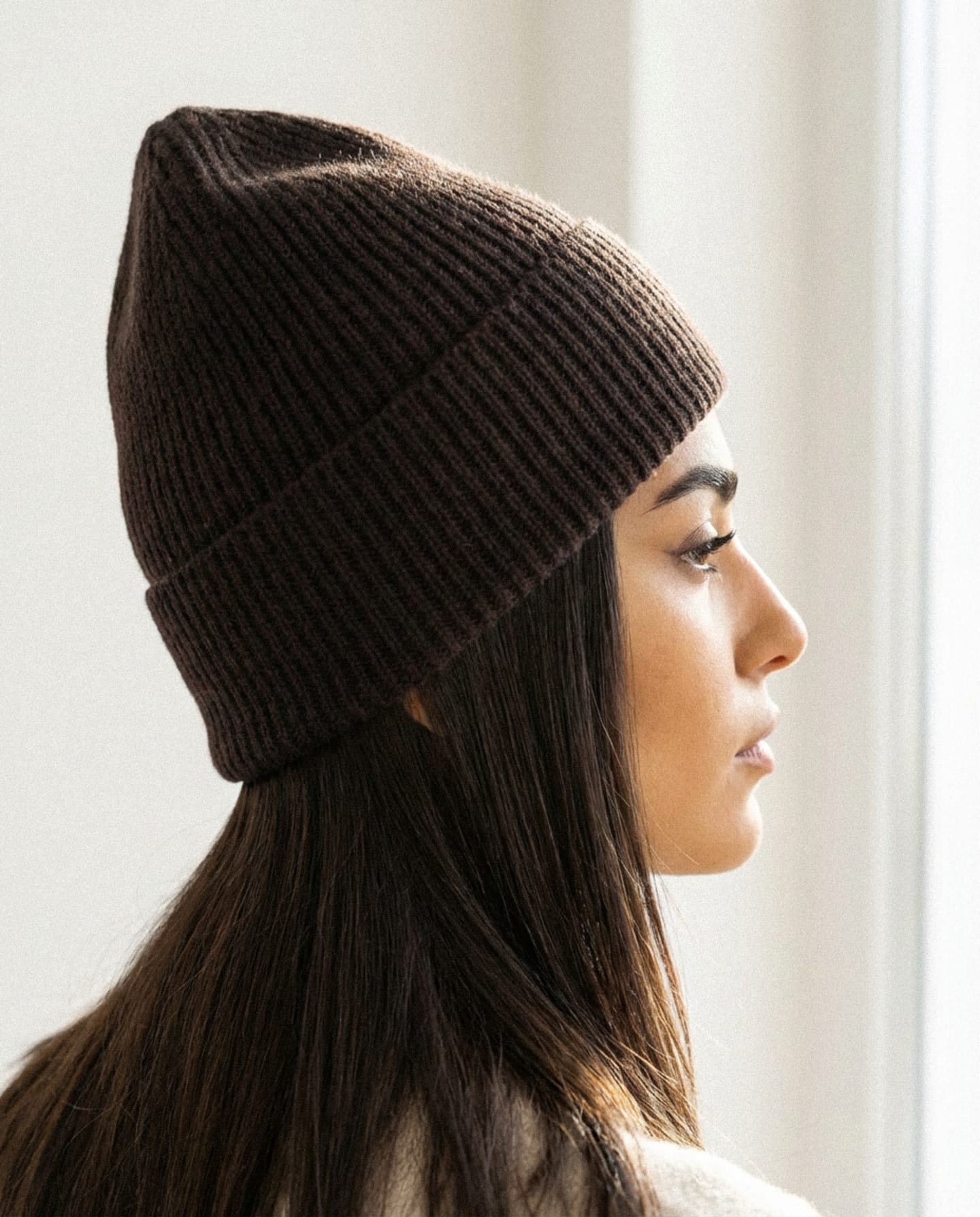 Woman wearing dark brown ribbed cashmere hat indoors, rear view