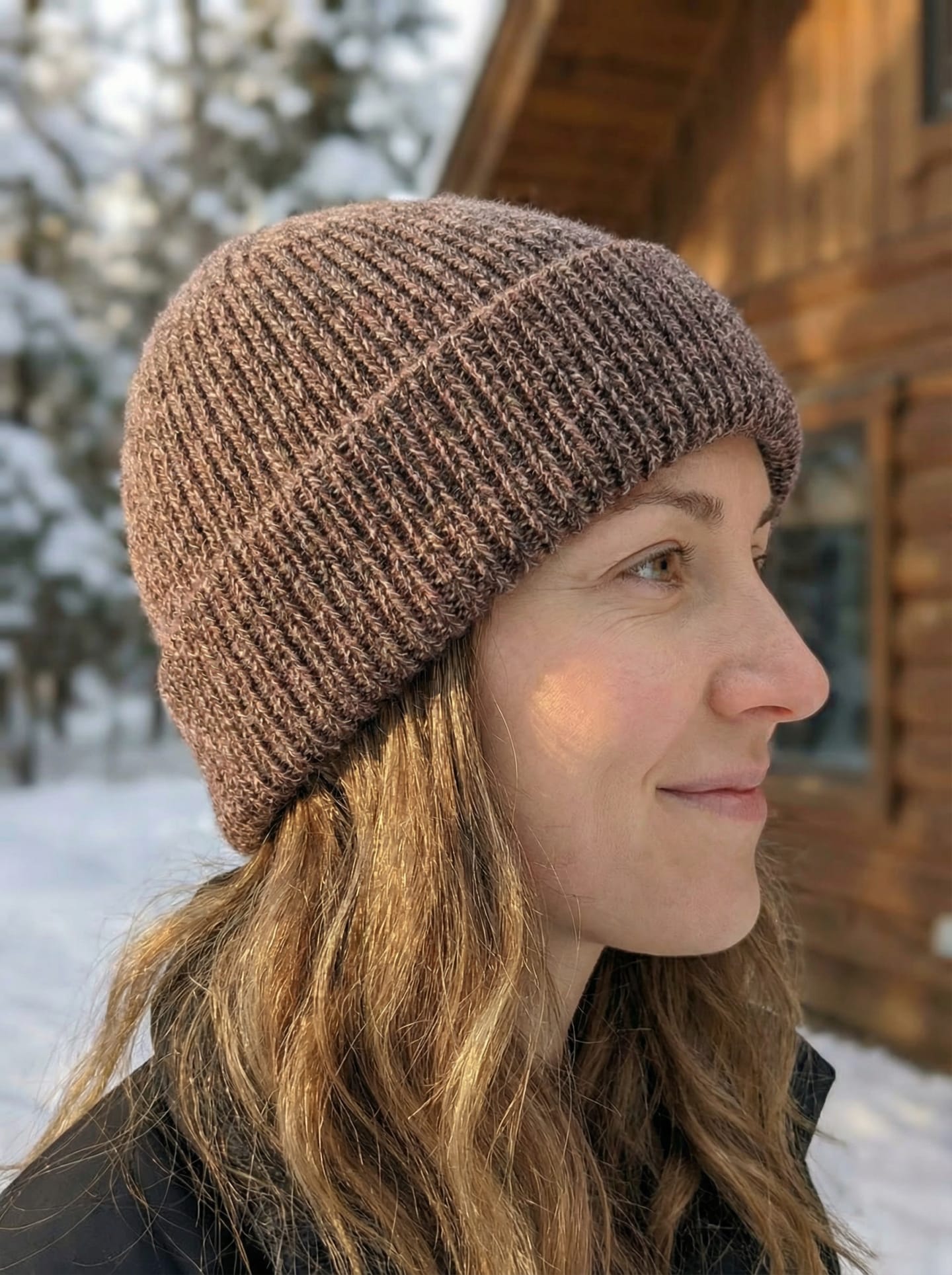Side view of woman outdoors wearing ribbed yak wool hat in mottled brown-pink