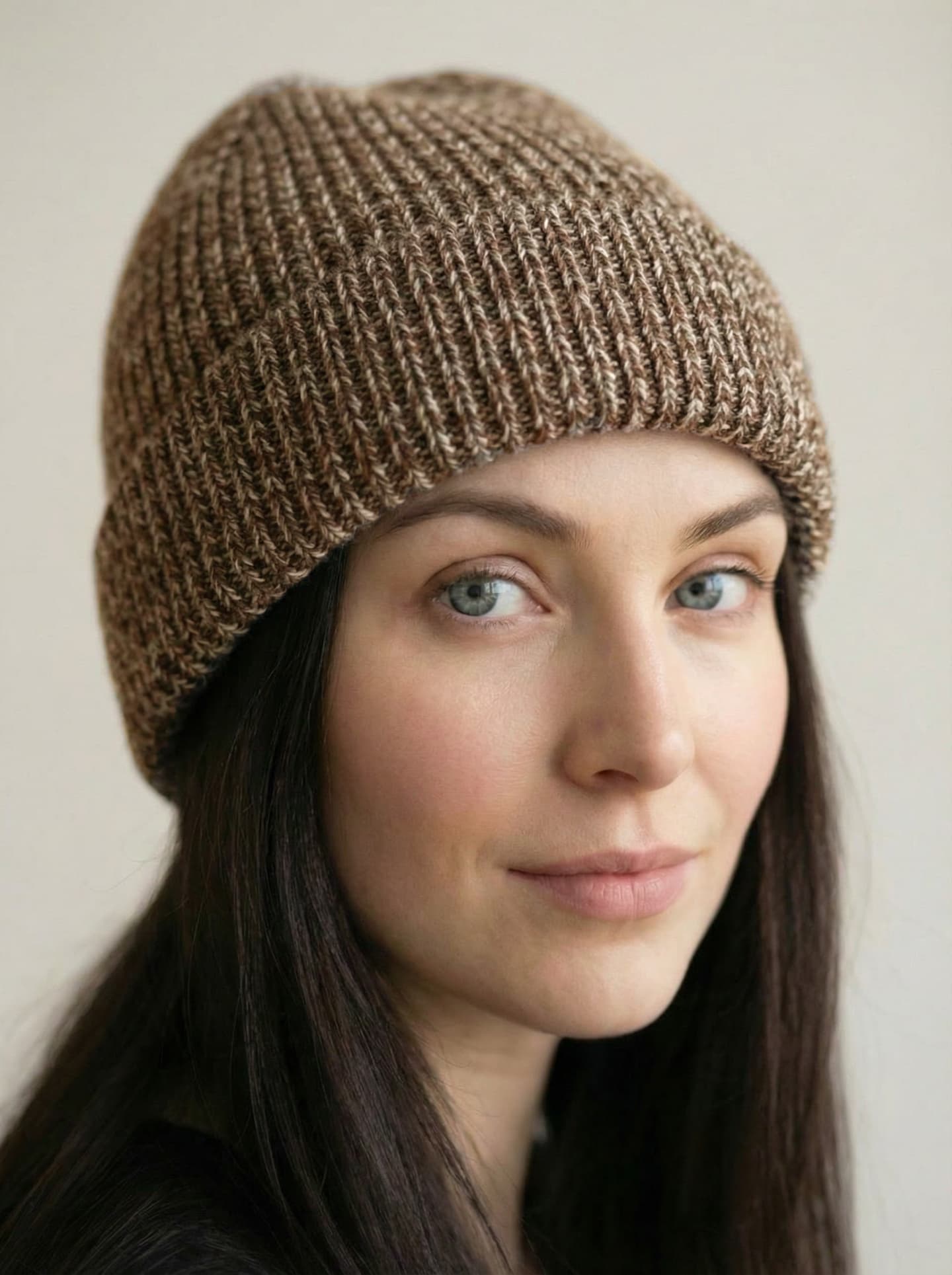 Front head shot view of woman wearing ribbed yak wool hat in mottled orange brown