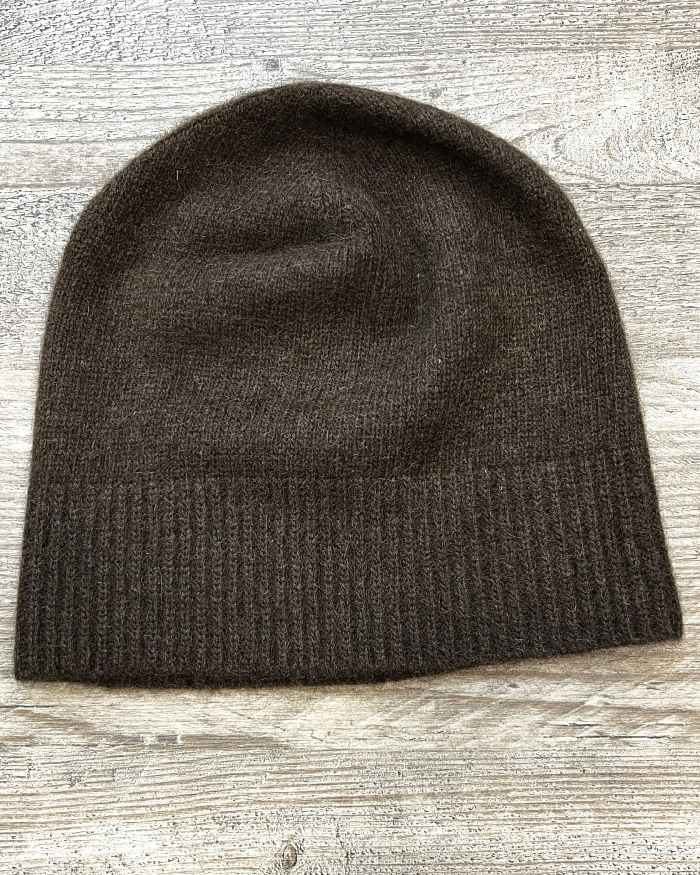 Dark brown yak wool beanie on neutral background, flat view