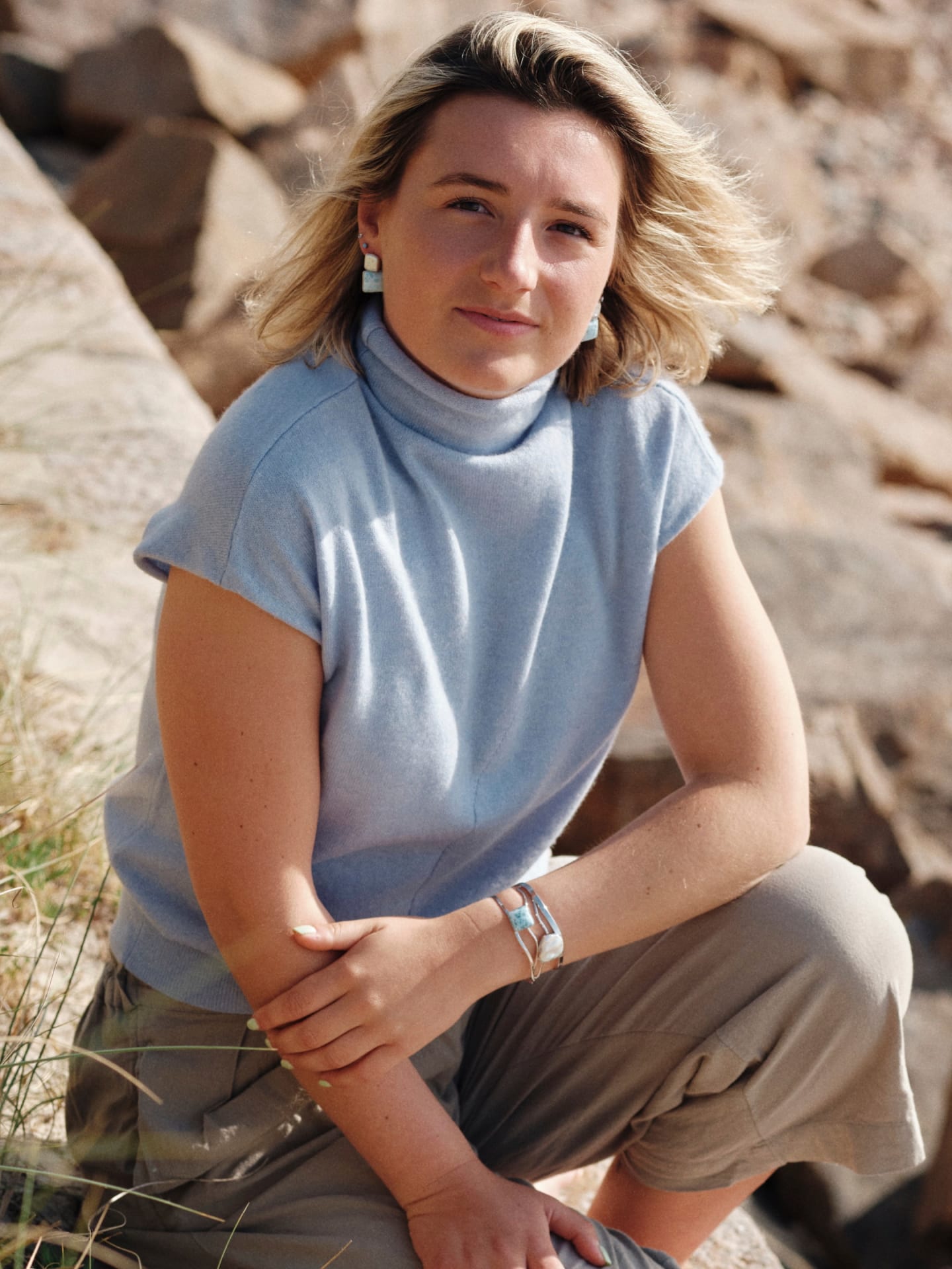 Model wearing the women's high neck cashmere vest in baby blue with the collar folded down, outdoor lifestyle shot – Unur