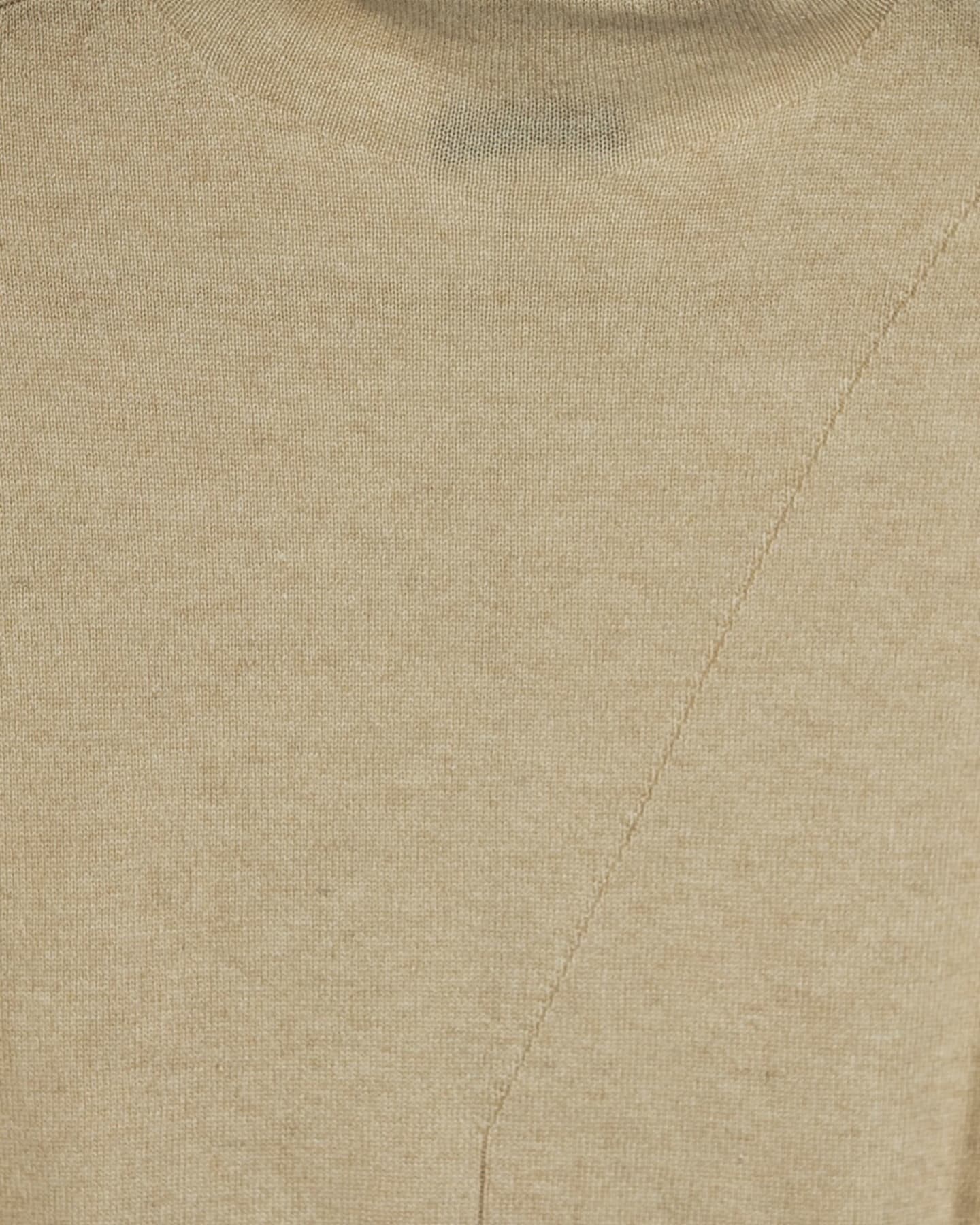 Close-up of the natural beige cashmere vest showing fine plain knit, faint fibre flecks, and the diagonal front panel seam – Unur