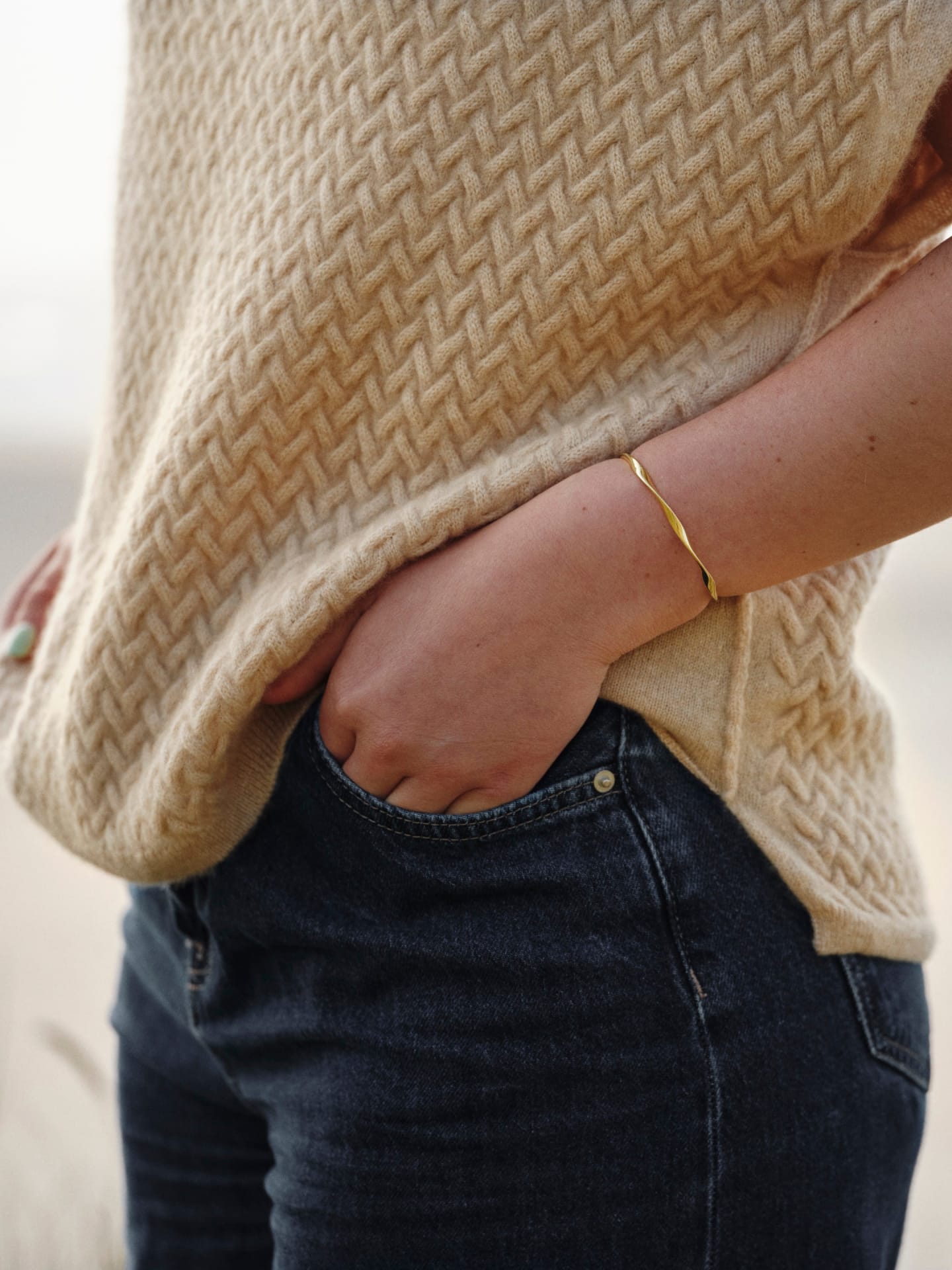 Side view of a model wearing natural beige luxury cable knit cashmere vest