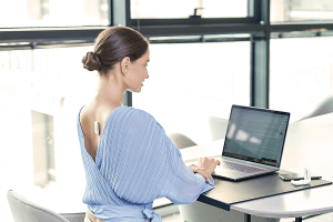 Woman wearing UPRIGHT GO 2 while working on laptop, demonstrating good posture in the office