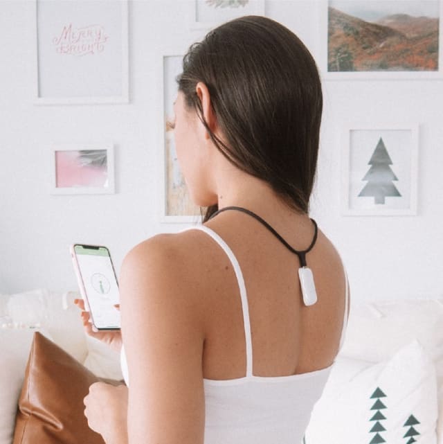 Woman with Upright Necklace on while she looks at the Upright app on her smartphone