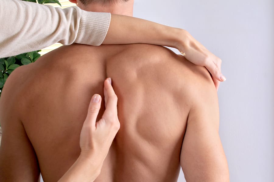 Man being checked for rounded shoulders by a doctor.