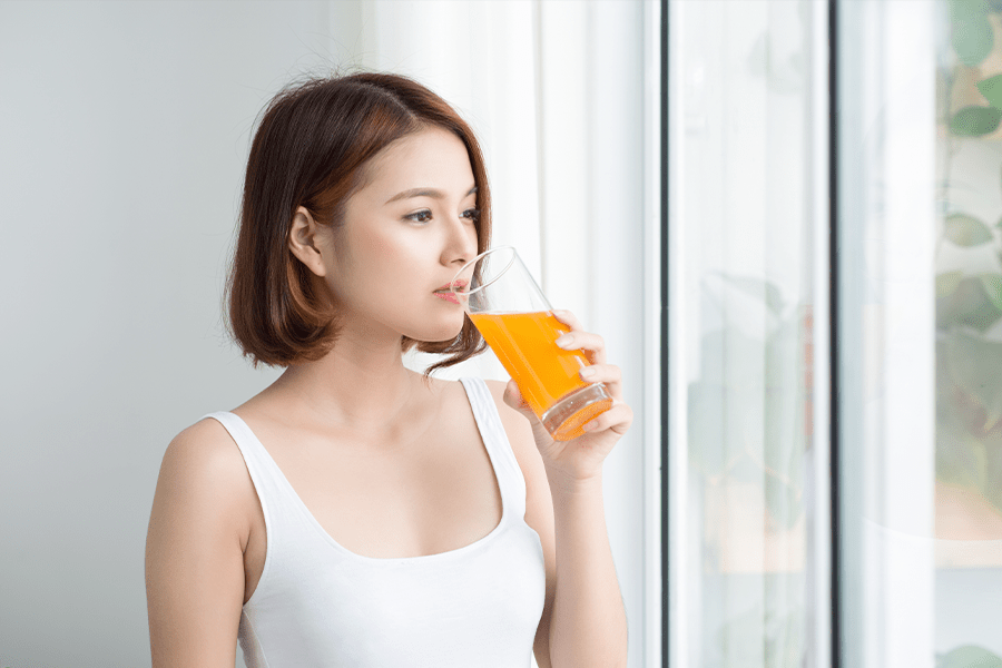 Woman drinking orange juice for strong, healthy muscles.