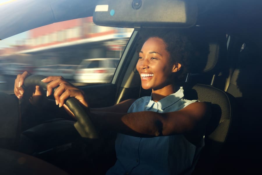 Woman smiling while driving with proper posture