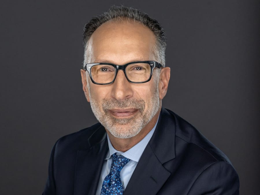 Daniel Fenster smiling wearing suit in front of gray background