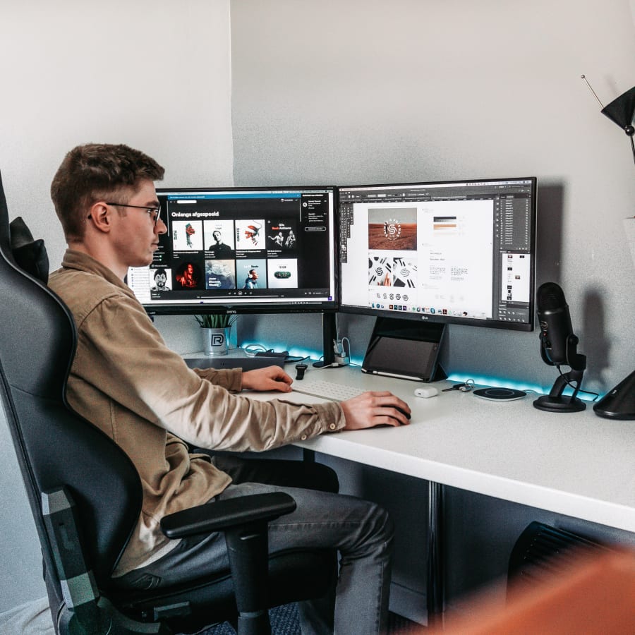 Man sitting in a chair with back support working on two monitors